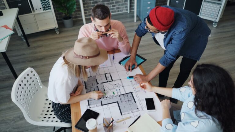 People reviewing renovation plans and documents around a table before hiring a contractor
