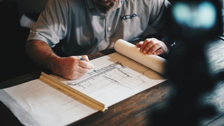Hands reviewing architectural plans with drawings spread across a desk